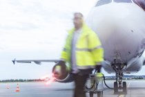 Controlador de tráfego aéreo que passa pelo avião no asfalto — Fotografia de Stock