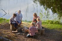 Бабушки и внуки наслаждаются костром на берегу озера — стоковое фото