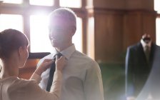 Портной регулирует галстук для бизнесмена в магазине мужской одежды — стоковое фото