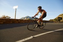 Male cyclist cycling on sunny corner — Stock Photo