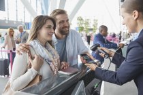 Представник служби підтримки клієнтів сканує QR-код смартфона під час реєстрації в аеропорту — стокове фото