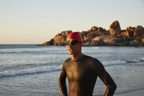 Male triathlete swimmer in wet suit on ocean beach — Stock Photo