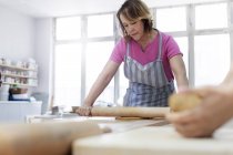 Femme argile à rouler avec rouleau à pâtisserie en studio — Photo de stock