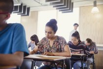 Studente di college femminile che fa test alla scrivania in classe — Foto stock