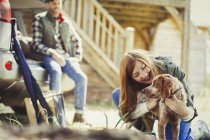 Woman petting dog outside cabin — Stock Photo