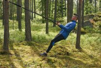 Runner using resistance band on tree in woods — Stock Photo
