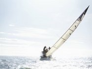 Scenic view of sailboat tilting on sunny ocean — Stock Photo