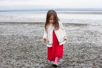 Mädchen im Kleid zu Fuß am Strand — Stockfoto