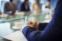 Empresário sentado à mesa de conferência na sala de conferências com as mãos apertadas — Fotografia de Stock