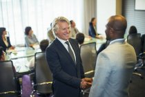 Усміхнені бізнесмени тремтять руками під час зустрічі в конференц-залі — стокове фото