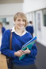 Портрет усміхненої студентки в шкільній формі, що стоїть в коридорі — стокове фото