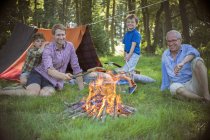 Garçon, père et grand-père se détendre près du feu de camp — Photo de stock