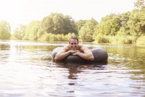Hombre flotando en el tubo interior en el lago - foto de stock