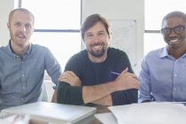 Портрет трех улыбающихся бизнесменов в офисе — стоковое фото