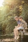 Отец и сын висят ногами в озере — стоковое фото