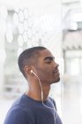 Portrait of young businessman listening to music on earphones — Stock Photo