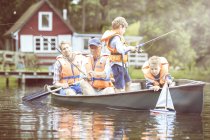 Brothers, father and grandfather fishing from canoe on lake — Stock Photo