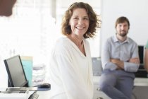 Portrait of businesswoman in office, colleague in background — Stock Photo
