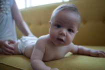 Portrait of little baby lying on front on yellow sofa — Stock Photo
