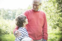 Grandfather and grandson hugging outdoors with ball — Stock Photo