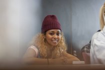 Portrait of smiling female university student writing down notes in classroom — Stock Photo