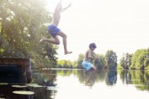 Отец и сын прыгают в озеро — стоковое фото