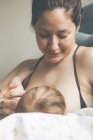 Портрет матері, яка посміхається і годує грудьми маленьку дитину — стокове фото