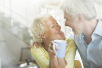 Couple plus âgé étreignant avec tasse de café — Photo de stock