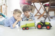 Frères jouant avec tracteur jouet sur le sol — Photo de stock