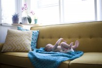 Маленький ребенок лежит на голубой ткани с поднятыми руками и ногами — стоковое фото