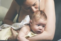 Мати тримає і цілує дитину, загорнуту в тканину після ванни — стокове фото