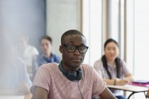Student mit Brille und Kopfhörer um den Hals blickt während der Vorlesung in die Kamera — Stockfoto