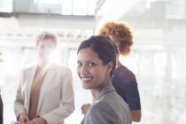 Портрет усміхненої бізнес-леді з колегами на задньому плані — стокове фото