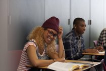 Studentin sitzt während Vorlesung am Schreibtisch und lächelt in die Kamera — Stockfoto