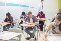 Студенты пишут свой GCSE экзамен в классе — стоковое фото
