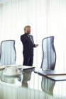 Чоловік стоїть в конференц-залі, розмовляючи на мобільному телефоні — стокове фото