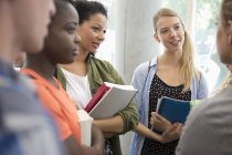 University students with books standing in corridor talking — Stock Photo