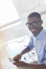 Retrato de un joven empresario sonriente usando un teléfono inteligente en la oficina — Stock Photo