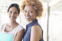 Portrait of two smiling women in modern office — Stock Photo