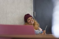 Estudiante universitario sonriente relajándose durante el descanso en el aula - foto de stock