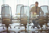 Businessman sitting behind blinds in conference room — Stock Photo
