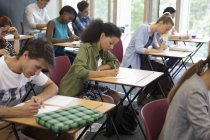 Estudantes universitários fazendo exame em sala de aula — Fotografia de Stock