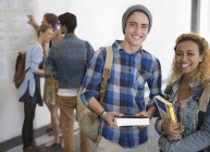 Portrait of two smiling university students standing in corridor — Stock Photo