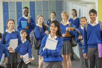 Portrait de groupe d'écoliers portant des uniformes scolaires debout dans le couloir et souriant — Photo de stock