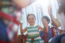 Menina sorrindo no carrossel no parque de diversões — Fotografia de Stock