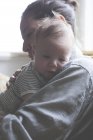 Портрет матері, що тримає маленьку дитину в смугастій футболці — стокове фото