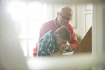 Caucasian grandfather and grandson writing at desk — Stock Photo