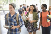 University students carrying books and walking to classroom — Stock Photo