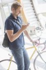 Людина використовує мобільний телефон і тримає велосипед — стокове фото