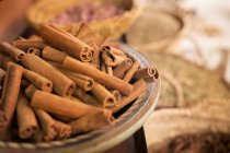 Cinnamon sticks on plate and other spices in background in spice market — Stock Photo